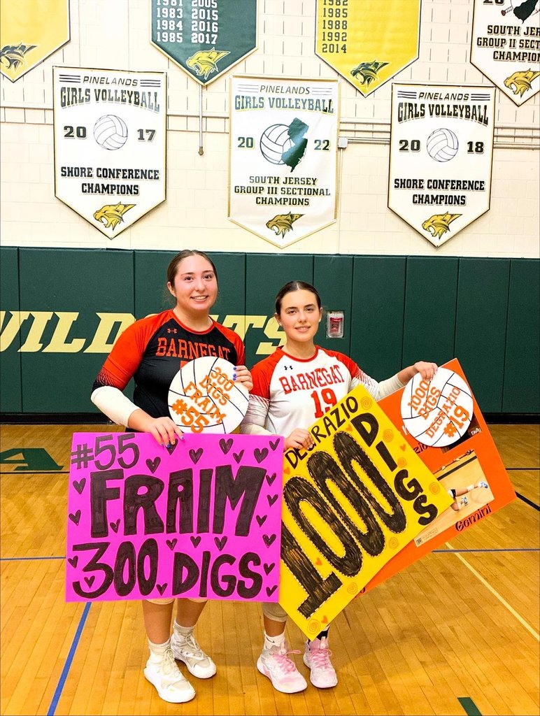 Image of the two girls holding signs celebrating their career digs. 