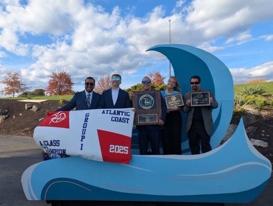 Image of the advisors posing with the banner and the awards that were received. 