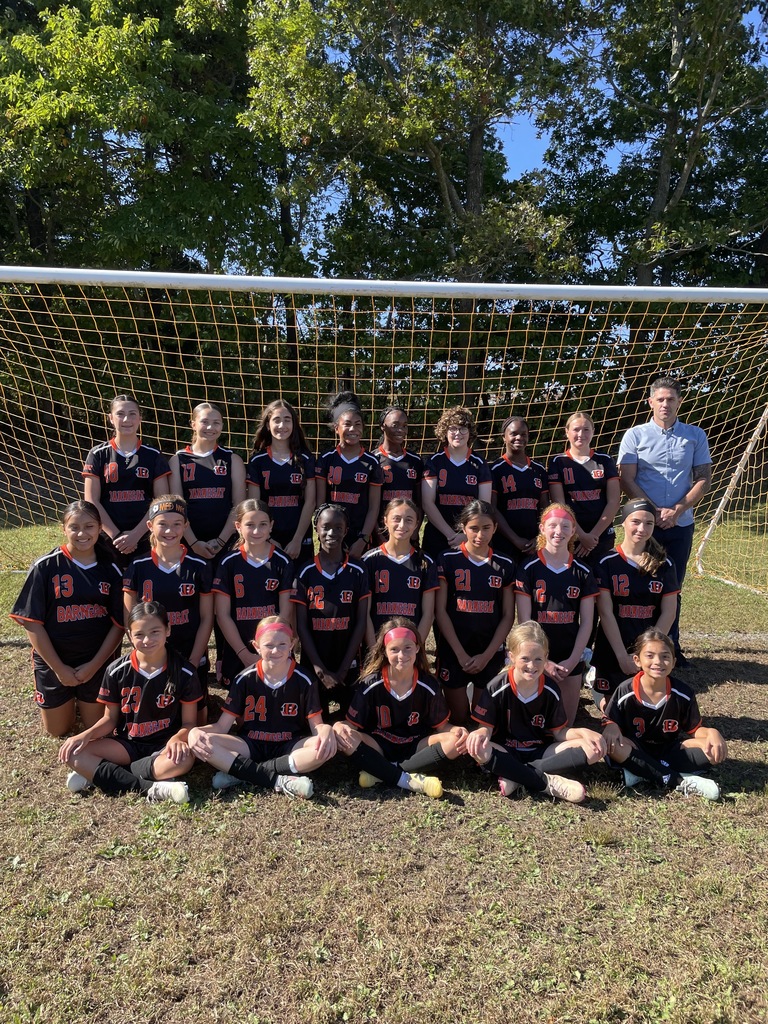 Image of the ROBMS girls soccer team posing with their coach in front of the goal. 