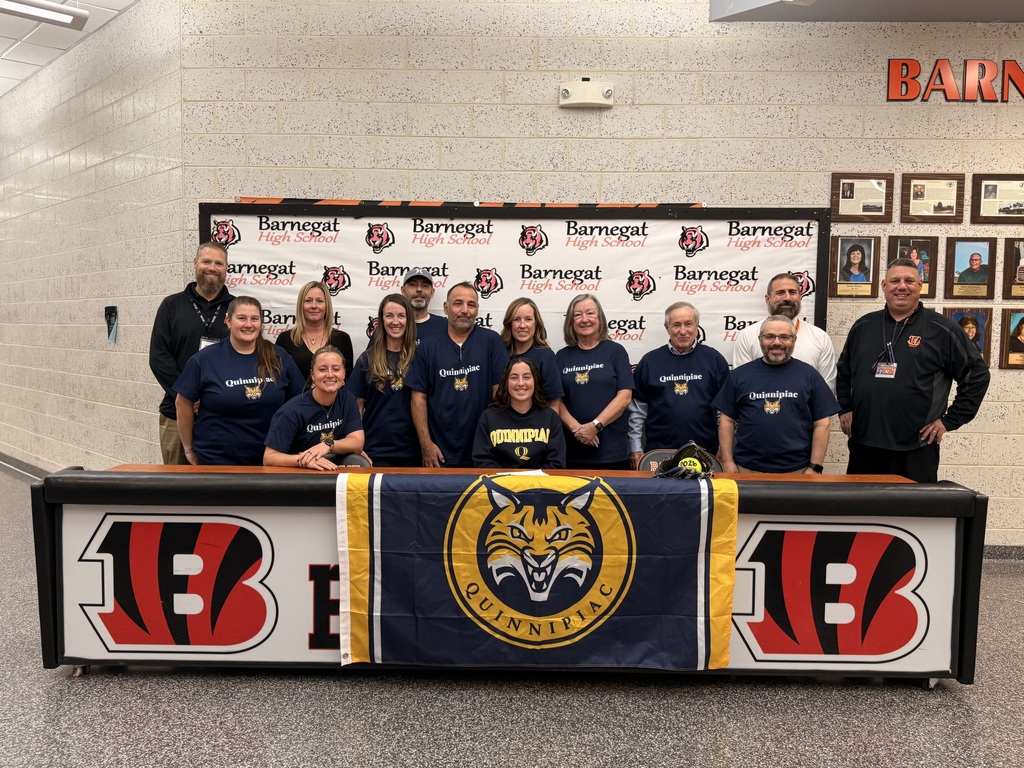 Image of Riley posing with family, coaches, building and district administrators. 