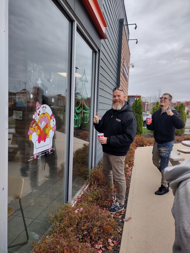Image of a student and teacher painting a Christmas tree with presents underneath it. 