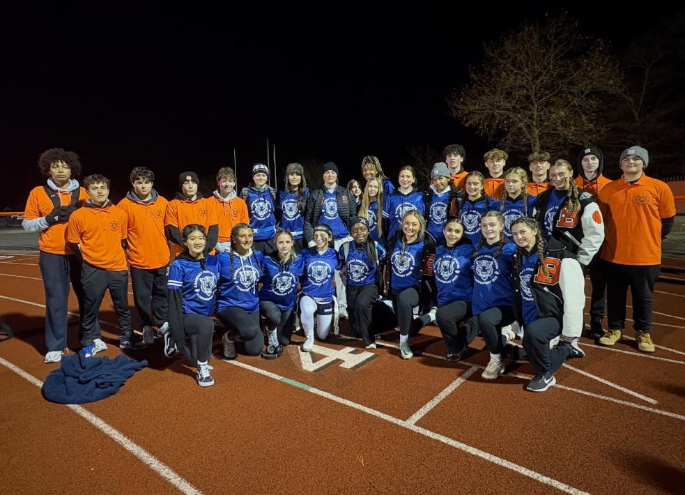 Image of the sophomore girls team posing with the student coaches on the track. 