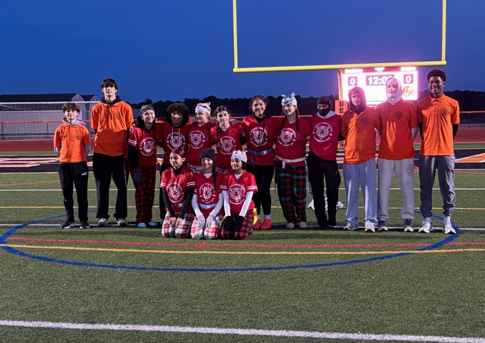 Image of the freshman girls team posing with the student coaches on the field. 