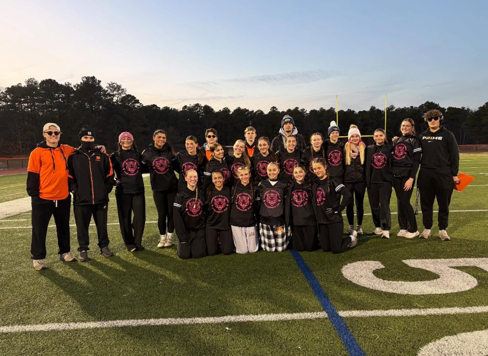 Image of the senior girls team posing with the student coaches on the field. 
