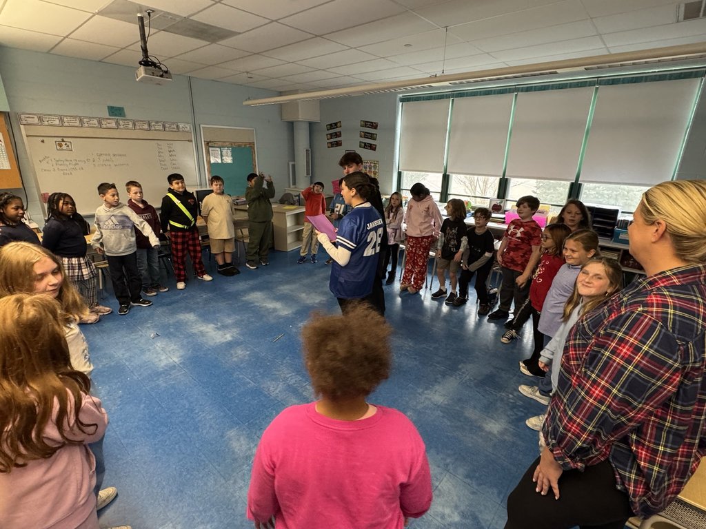 Image of a 4th-grade class in a circle with two Dylan's Wings students in the middle leading an activity. 