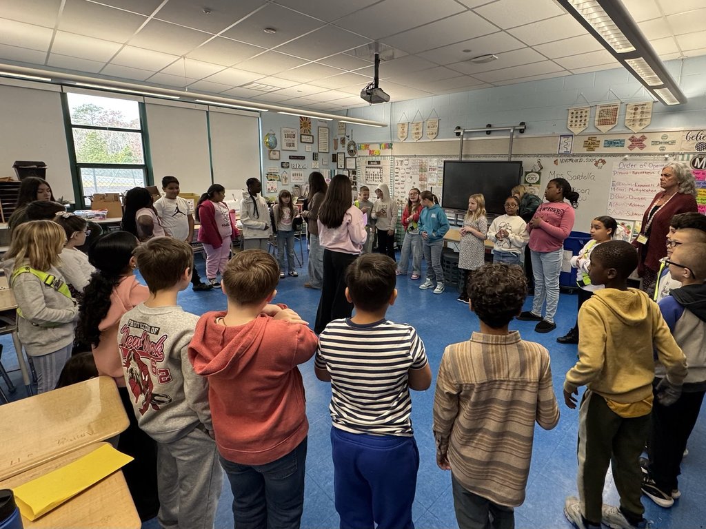 Image of a 4th-grade class in a circle with two Dylan's Wings students in the middle leading an activity. 