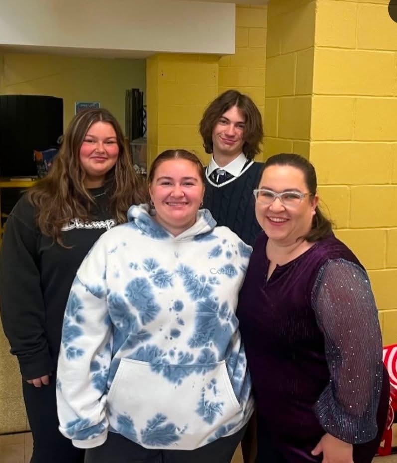 Image of the three students posing with their chorus teacher. 