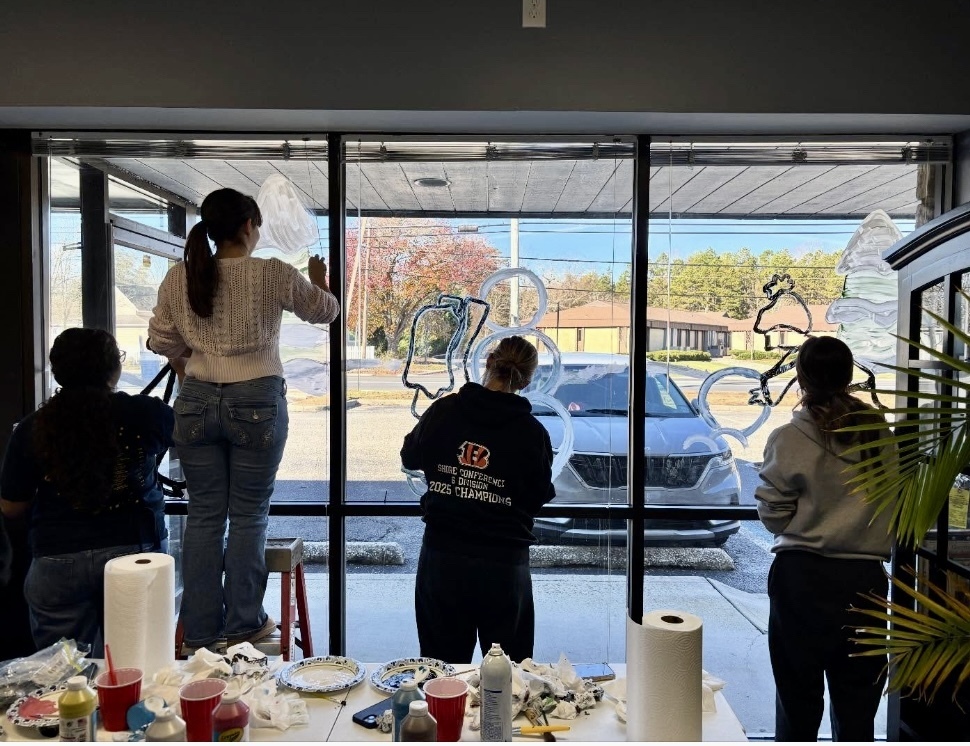 Image of the students painting festive winter scenes on the inside of the windows. 