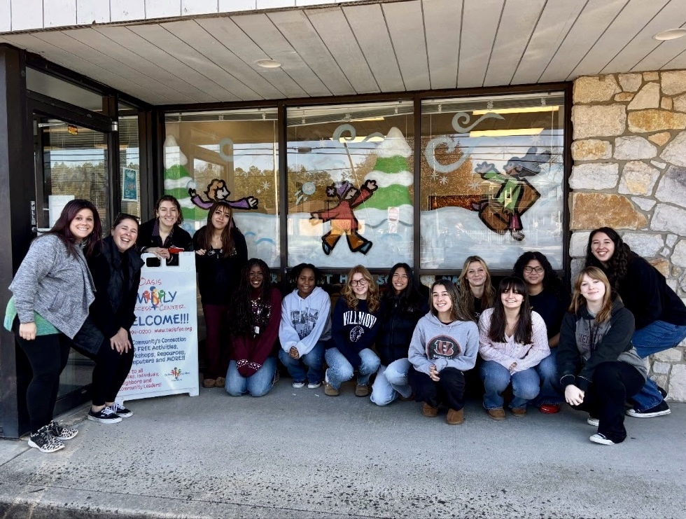 Image of the BHS National Art Honor Society students and staff posing in front of their painted window display. 