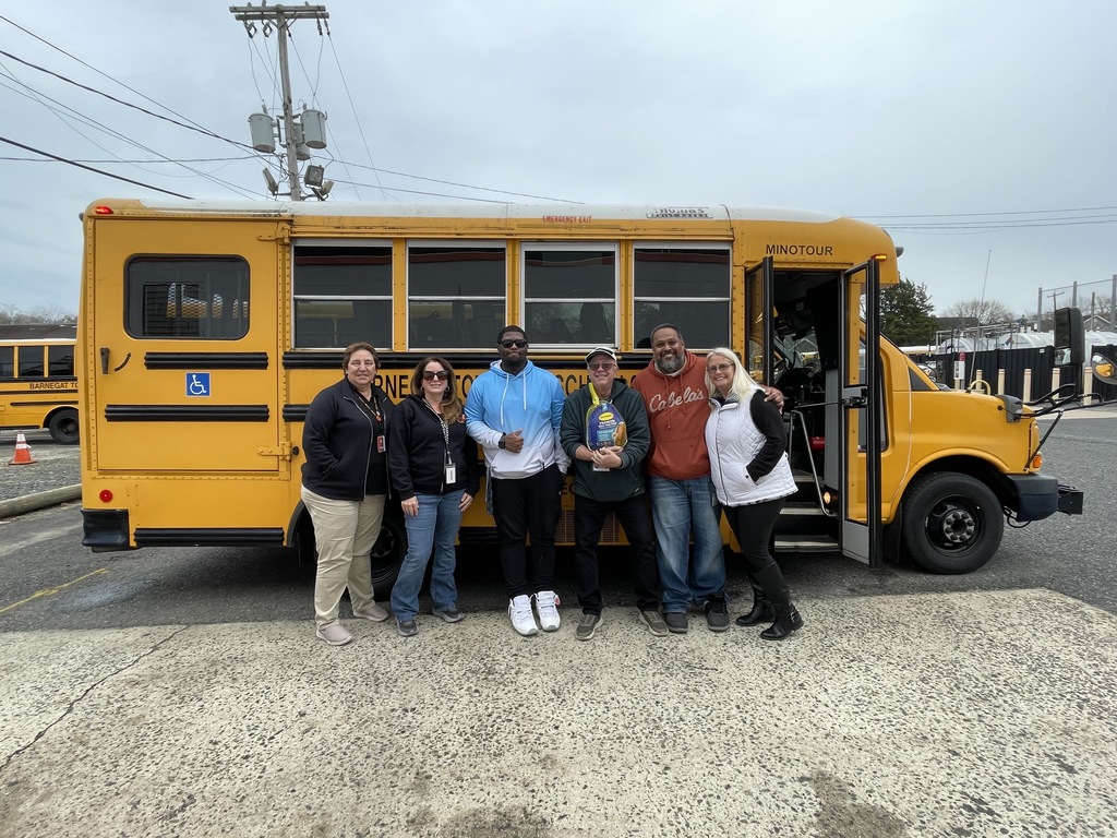 Image of the transportation department posing in front of a bus before making deliveries to families. 