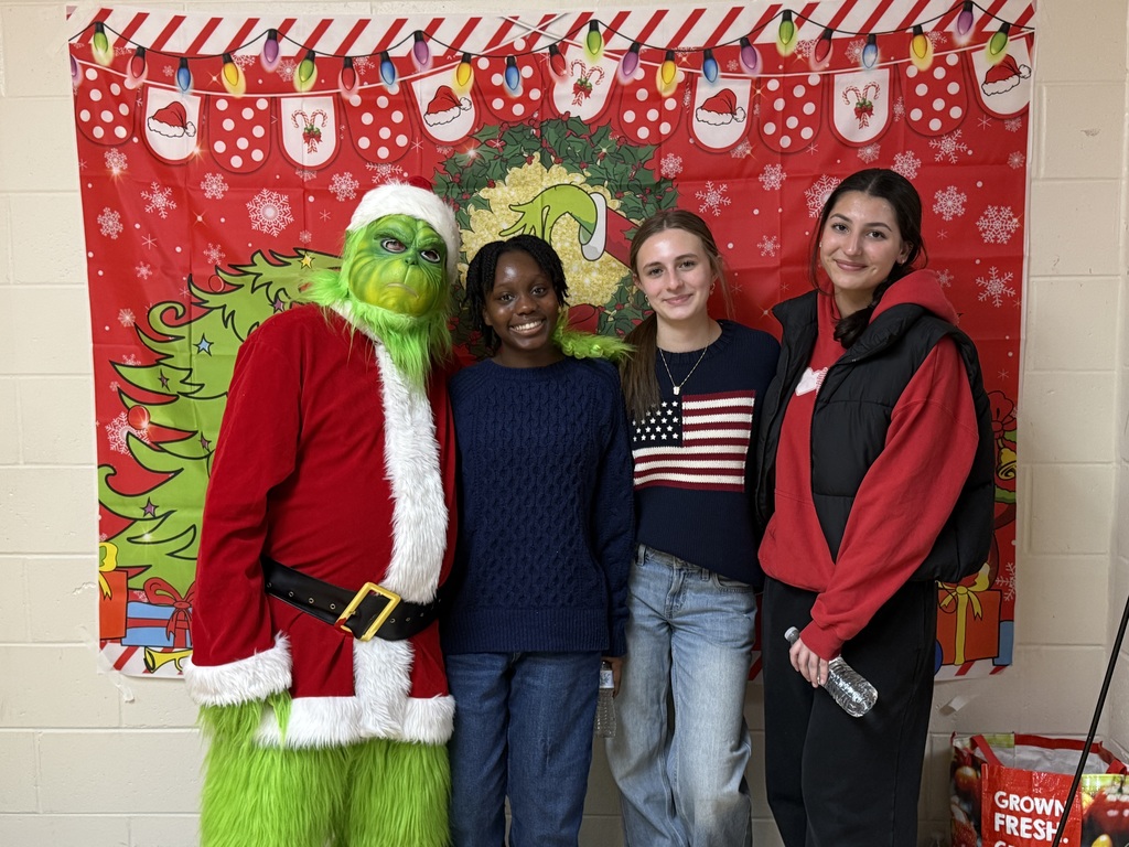 Image of the Grinch posing with three student volunteers.