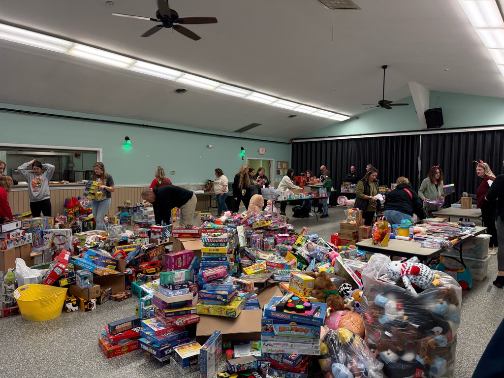 Image of the officers and Paws For A Cause members sorting items collected in the toy drive separated by category. 