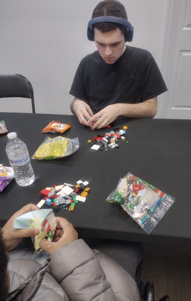 Image of a student sitting at a table putting together a pack of legos. 