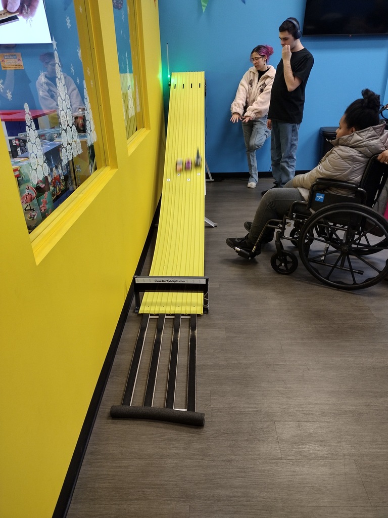 Image of three students watching the racecars they made race down the track. 