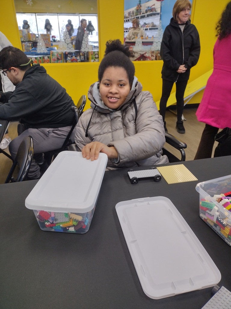 Image of a student sitting at a table with a container of legos.  