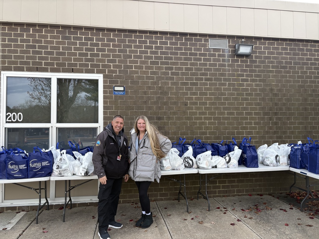 Image of the Collins School security guard and the counselor posing in front of the bags of food.  