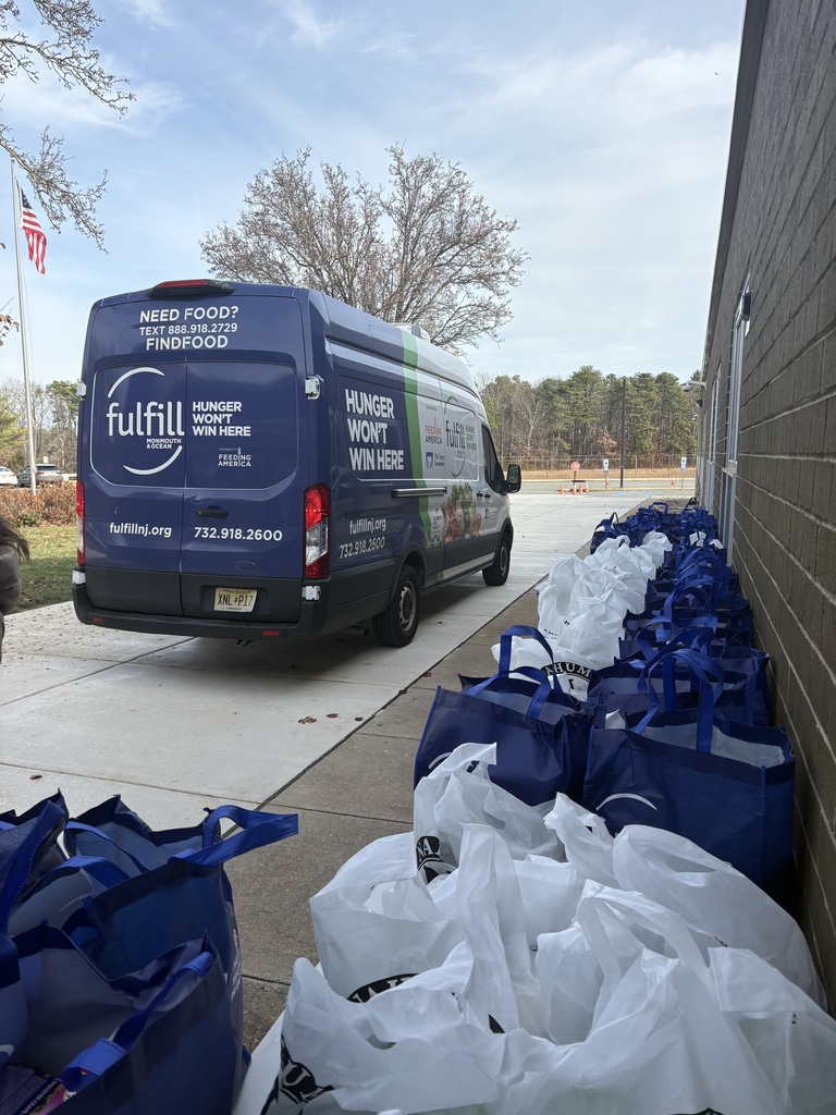 Image of the Fulfill Mobile Pantry truck and all the bags of food that were donated on tables outside of the Collins School. 