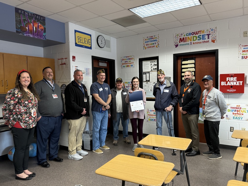 Image of the first place winner posing with District and building administrators along with members of the VFW. 