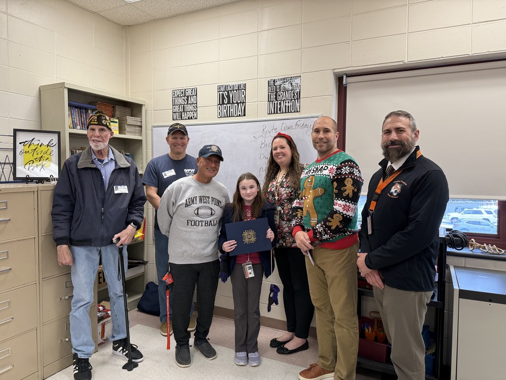 Image of the third place winner posing with District and building administrators along with members of the VFW. 