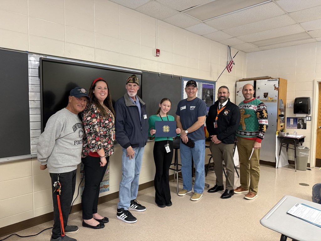Image of the second place winner posing with District and building administrators along with members of the VFW. 