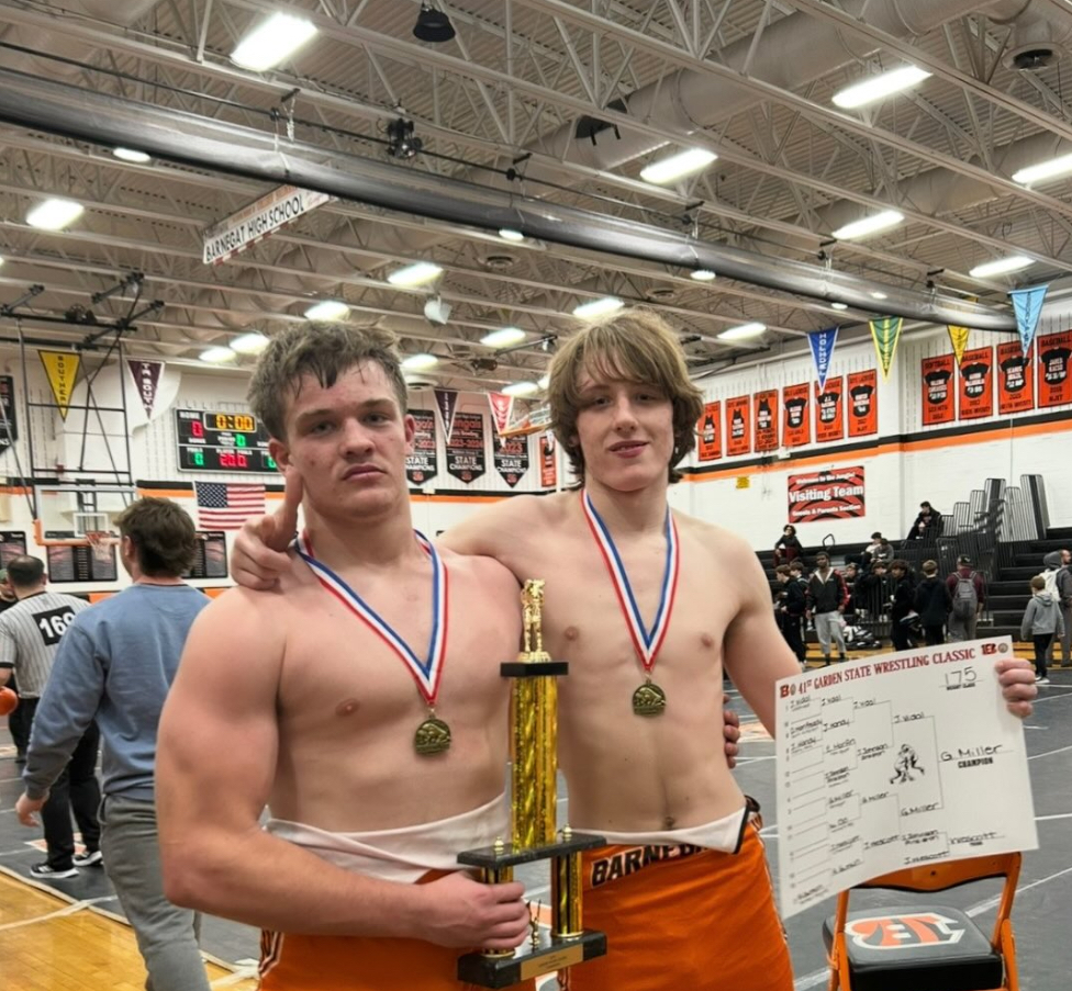 Image of two wrestlers posing with medals and trophy. 