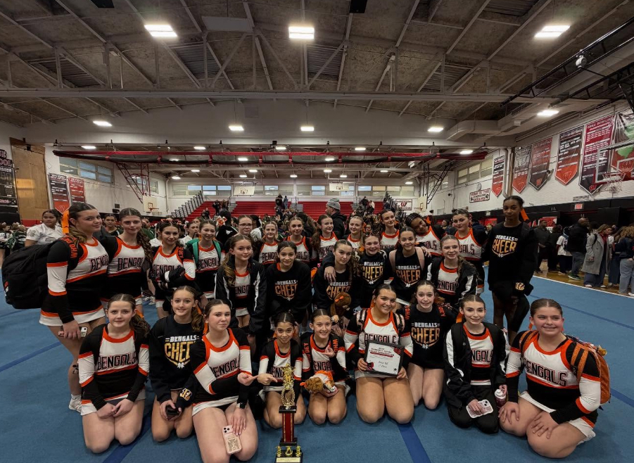 Image of the ROBMS Cheerleaders posing on the mat with their trophies. 