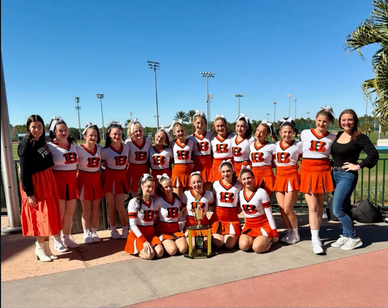 Image of the BHS cheerleaders and coaches posing with their trophy. 