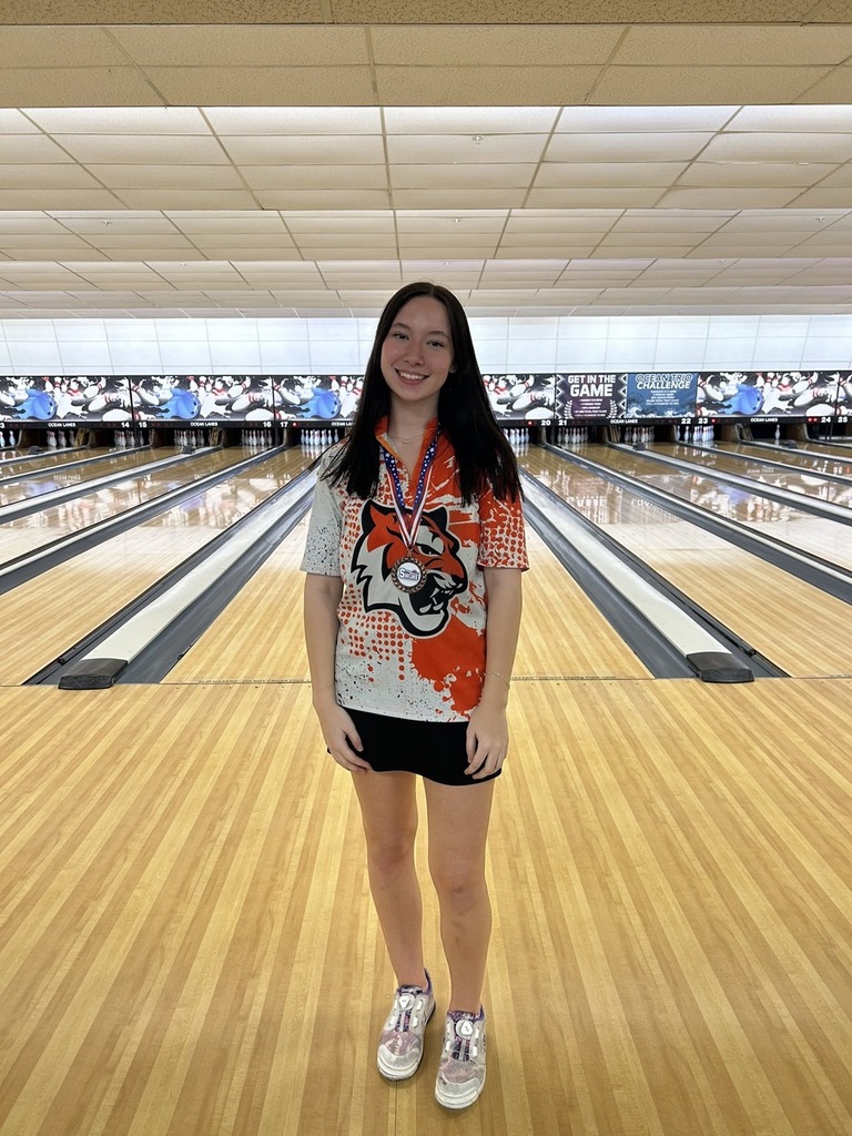 Image of Jamie wearing her third place medal around her neck standing in front of her lane. 