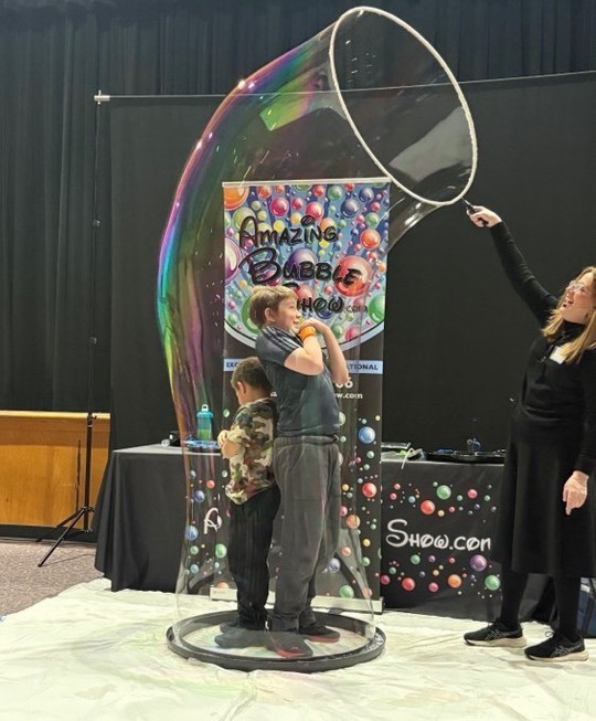 Image of two students being encased in a bubble by the presenter.