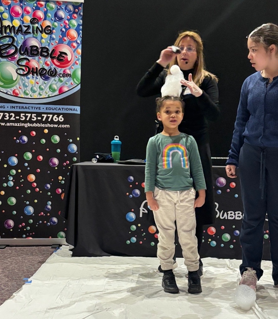 Image of student standing in front of the presenter who is holding bubbles in her hand.  
