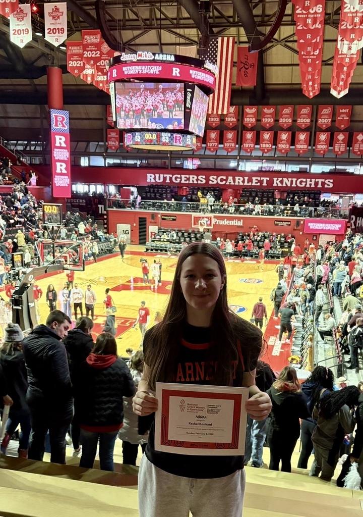 Image of Rachel holding a certificate with the Rutgers basketball court behind her.