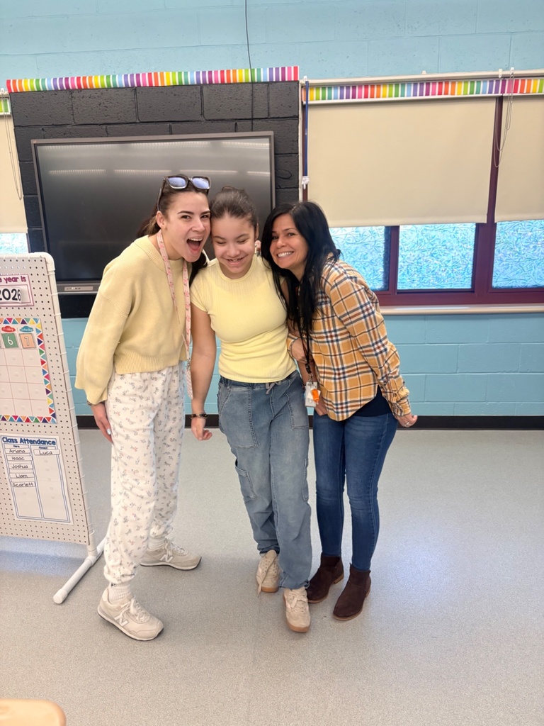 Image of a student posing with two staff members wearing yellow.