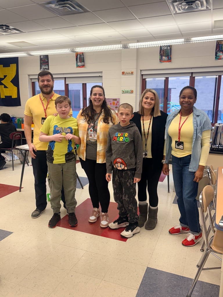 Image of two  students posing with four adults all wearting yellow.