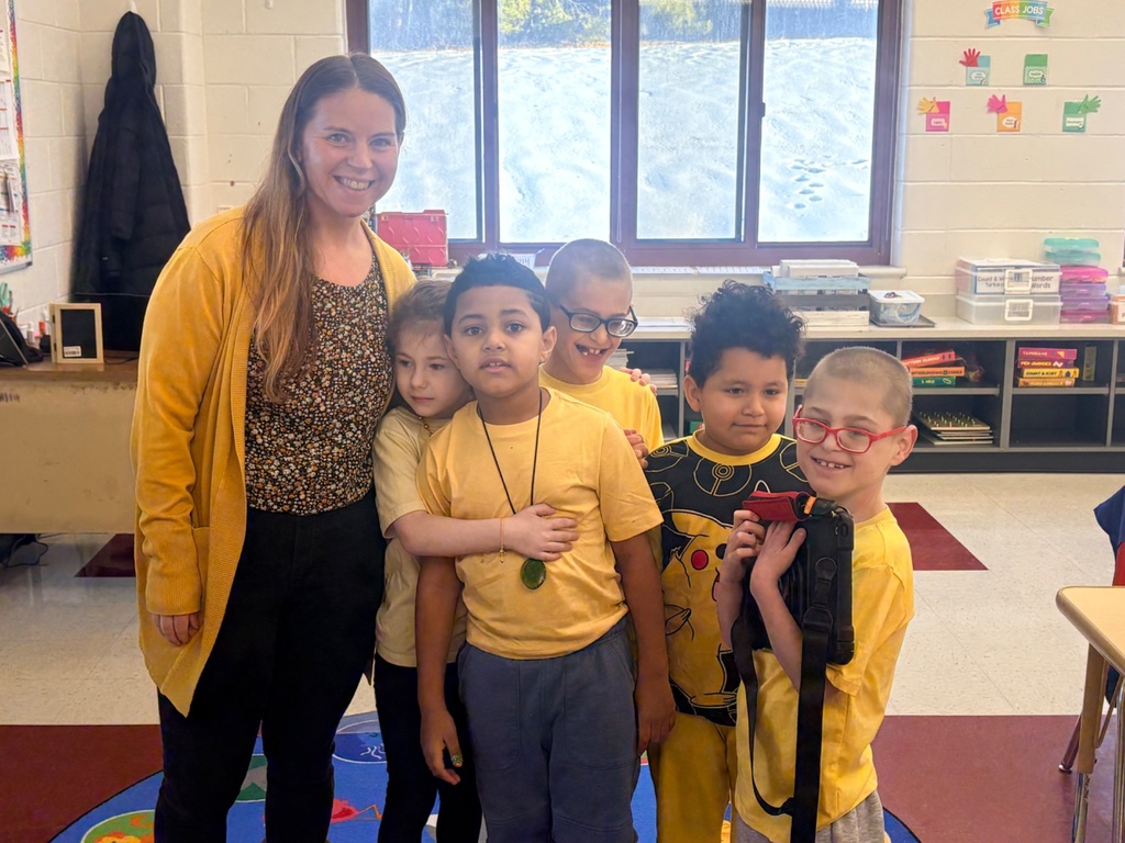 Image of an ACES class wearing yellow posing with the teacher. 
