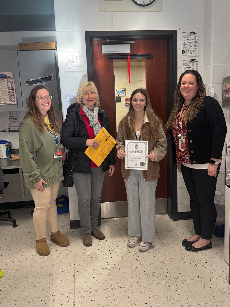Image of Emily posing with a representative of the Optimist Essay Contest, a district administrator,  and a building administrator. 