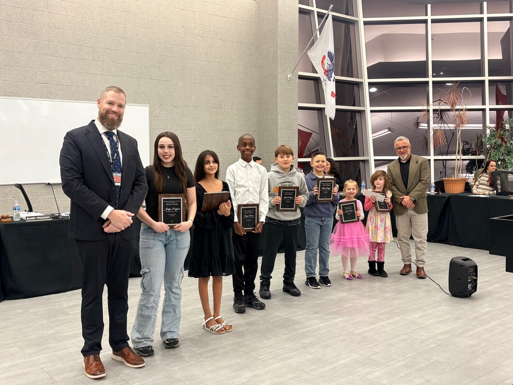 Image of the UPstanders holding their plaques, posing with the Superintendent and Board President. 