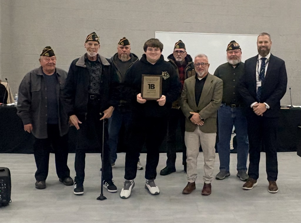 Image of Edward holding his plaque, posing with the Superintendent, Board President, and five VFW representatives.  