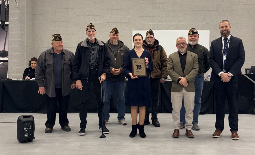 Image of Catherine holding her plaque, posing with the Superintendent, Board President, and five VFW representatives.  