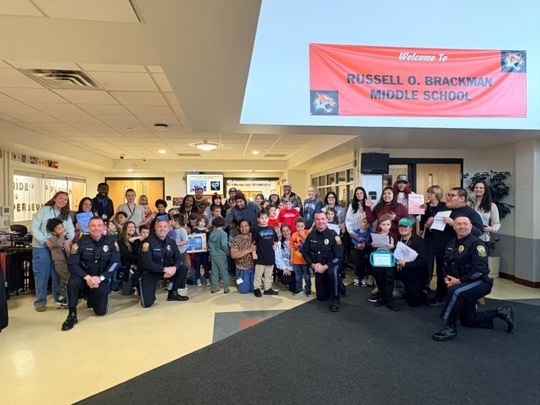 Image of the ACES students and staff posing in the main lobby of the school with four Barnegat police officers. 
