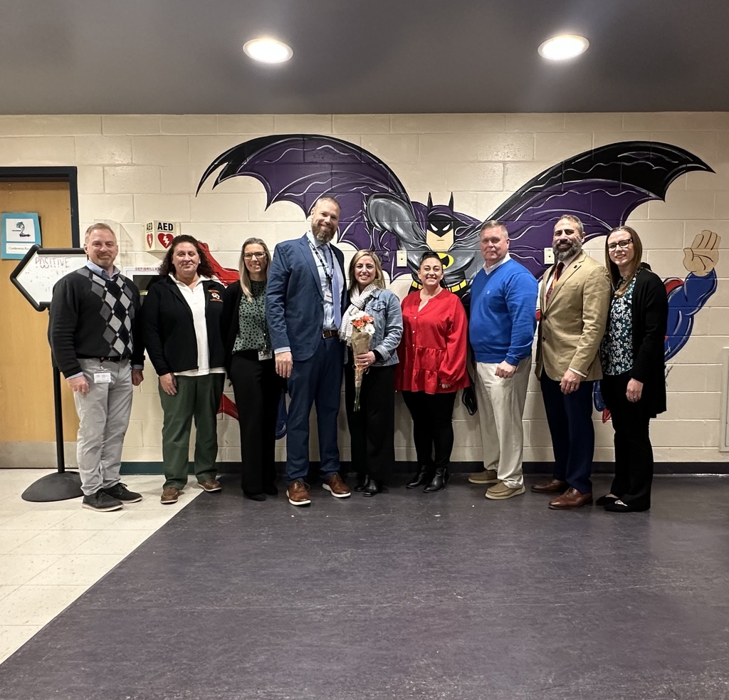 Image of Ms. DeGrazio holding a bouquet of flowers posing with district and building administrators. 