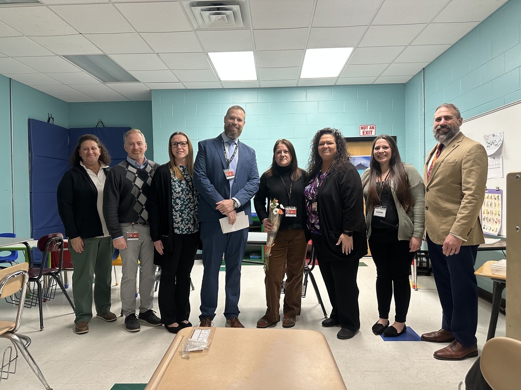 Image of Mrs. Greco holding a bouquet of flowers posing with district and building administrators. 