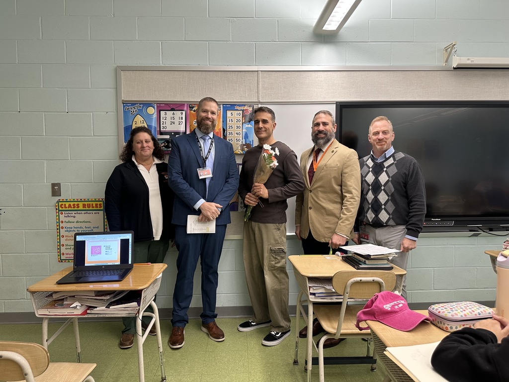 Image of Mr. DeGrazio holding a bouquet of flowers posing with district administrators. 