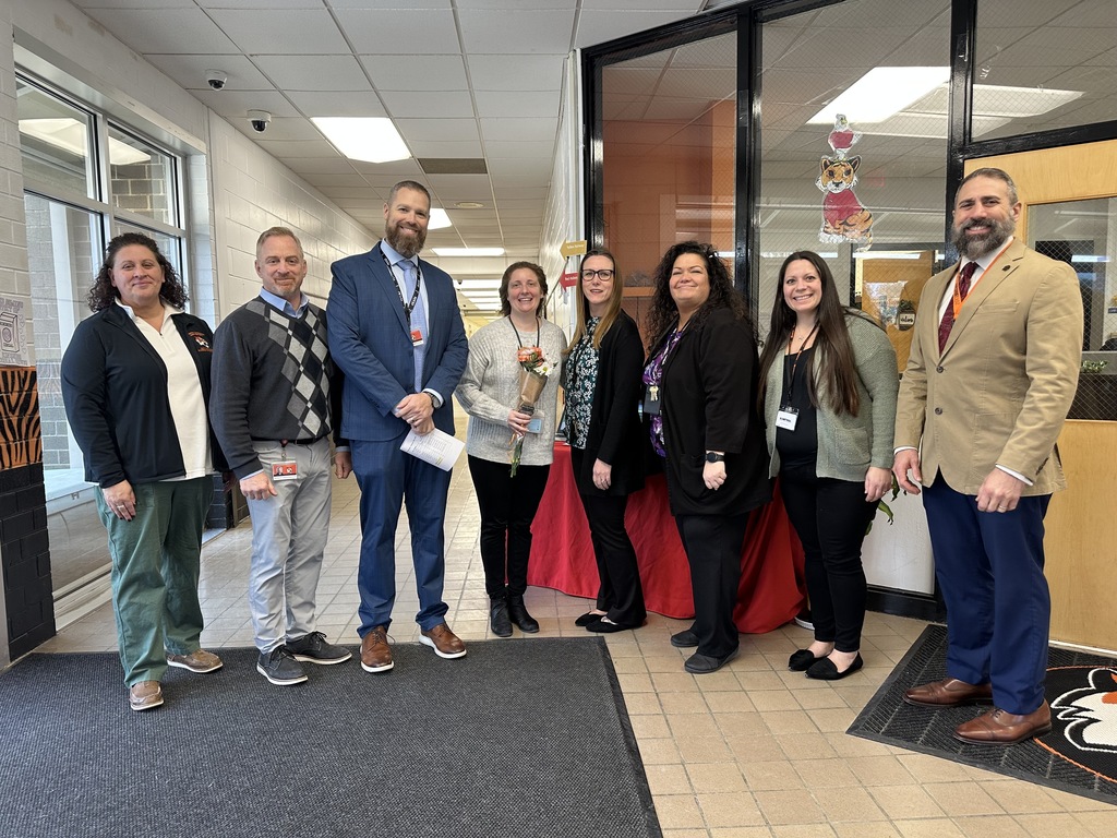 Image of Ms. Reed holding a bouquet of flowers posing with district and building administrators. 