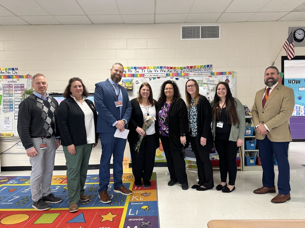 Image of Ms. Cannizzaro holding a bouquet of flowers posing with district and building administrators. 