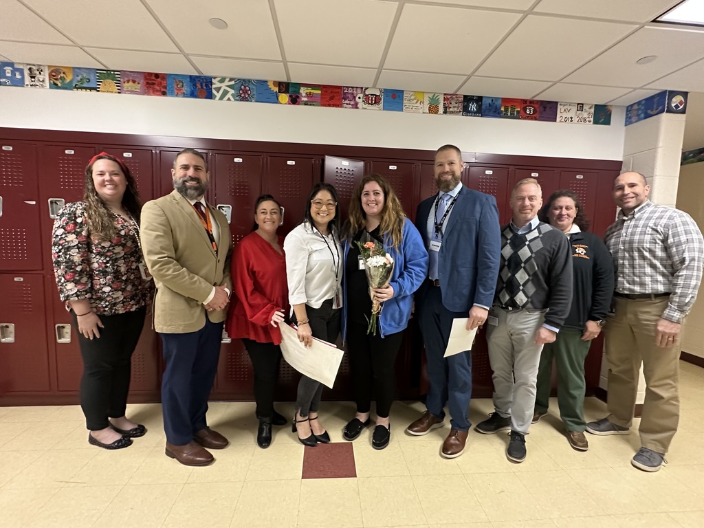 Image of Ms. Fontana holding a bouquet of flowers posing with district and building administrators. 