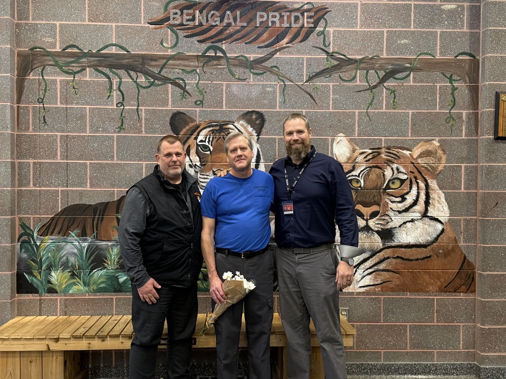 Image of Mr. Willis holding a bouquet of flowers posing with the Educational Facilities Coordinator and the Superintendent. 