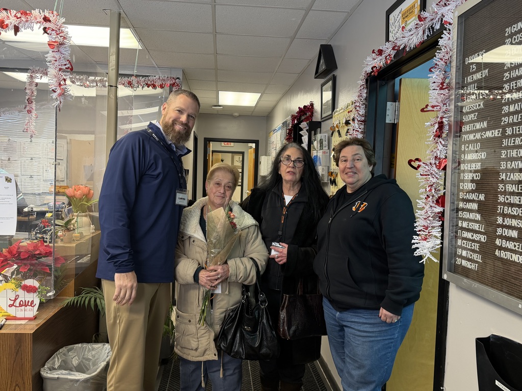 Image of Ms. Kennedy holding a bouquet of flowers posing with the Superintendent, Transportation Coordinator, and a transportation employee. 