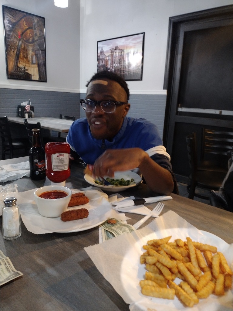 Image of a male student sitting at a table eating lunch. 
