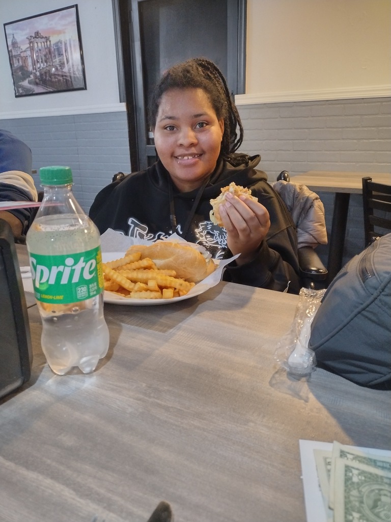 Image of a female student sitting at a table eating lunch. 