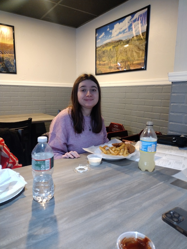 Image of a female student sitting at a table eating lunch. 
